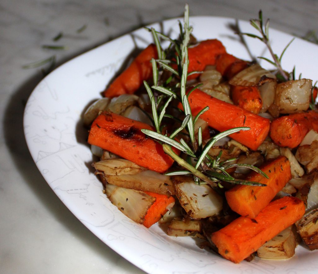 Plate of caramelized oven-roasted vegetables with a piece of rosemary