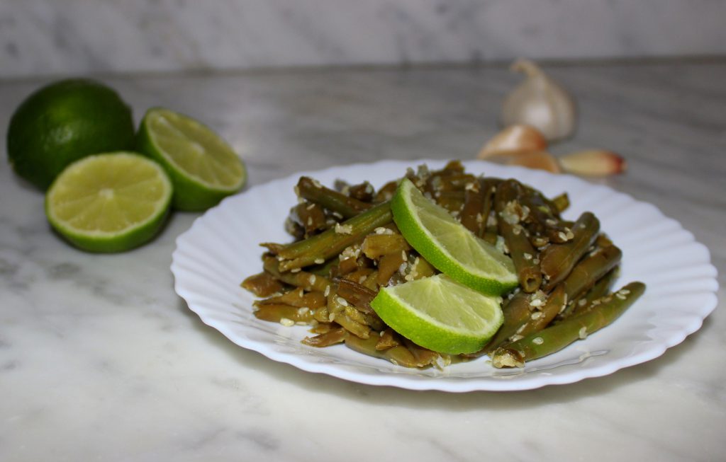 A plate of quick and easy exotic green beans with lime slices on top