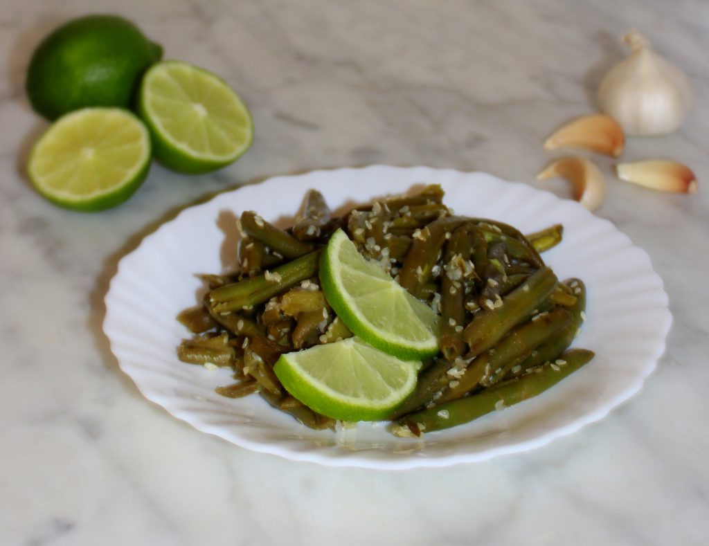 A plate of quick and easy exotic green beans with lime slices on top