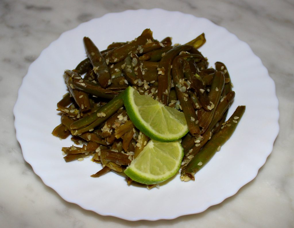 A plate of quick and easy exotic green beans with lime slices on top