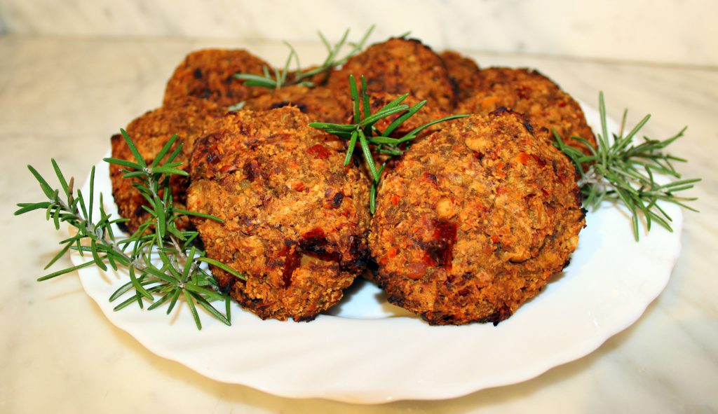 Eggplant and sundried tomato vegan burger patties on a plate with rosemary