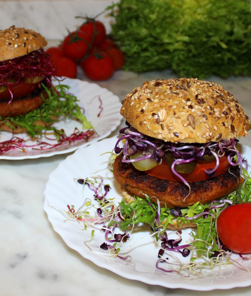 Eggplant and sundried tomato vegan burger in a bun with vegetables and purple sprouts