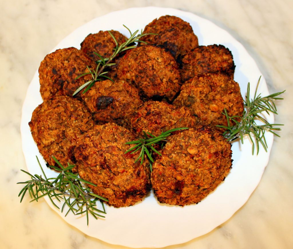 Eggplant and sundried tomato vegan burgers on a plate with rosemary