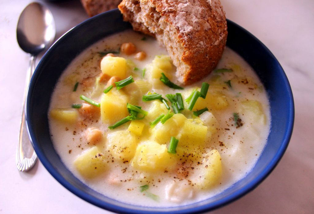 Creamy vegan potato leek soup served with a piece of bread