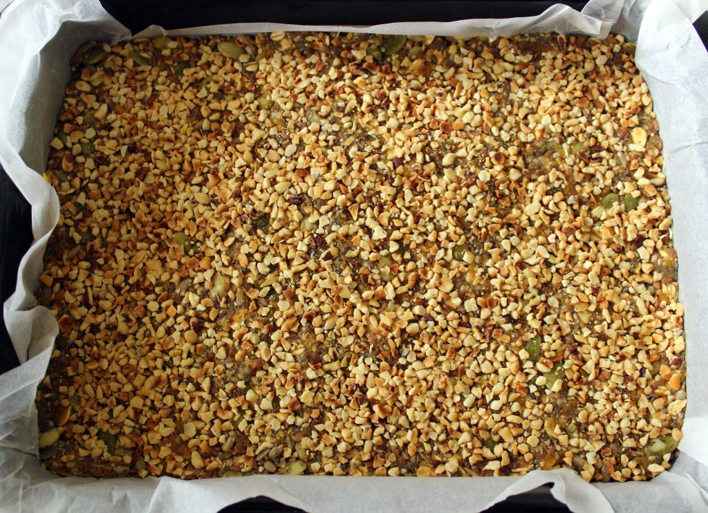 Mixture for healthy vegan no-bake protein bars before cooling covered with hazelnuts