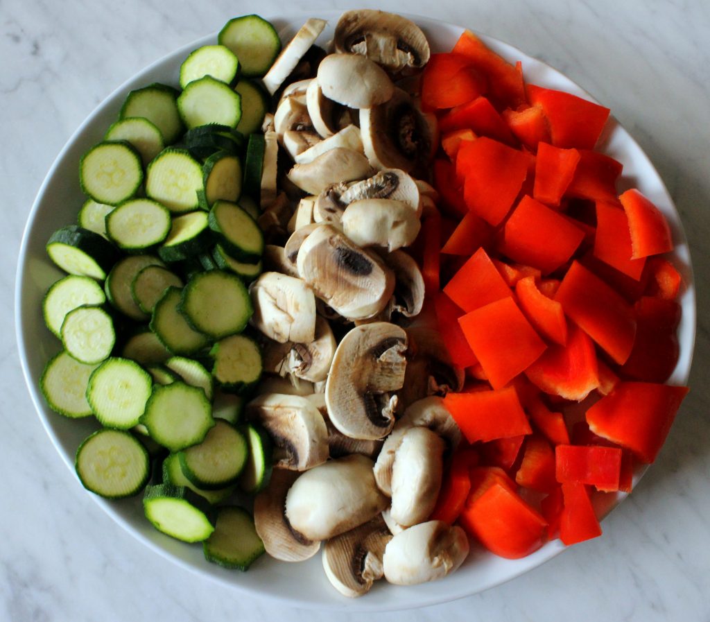 Slices zucchini, mushrooms and red bell peppers on a plate resembling the Italian flag