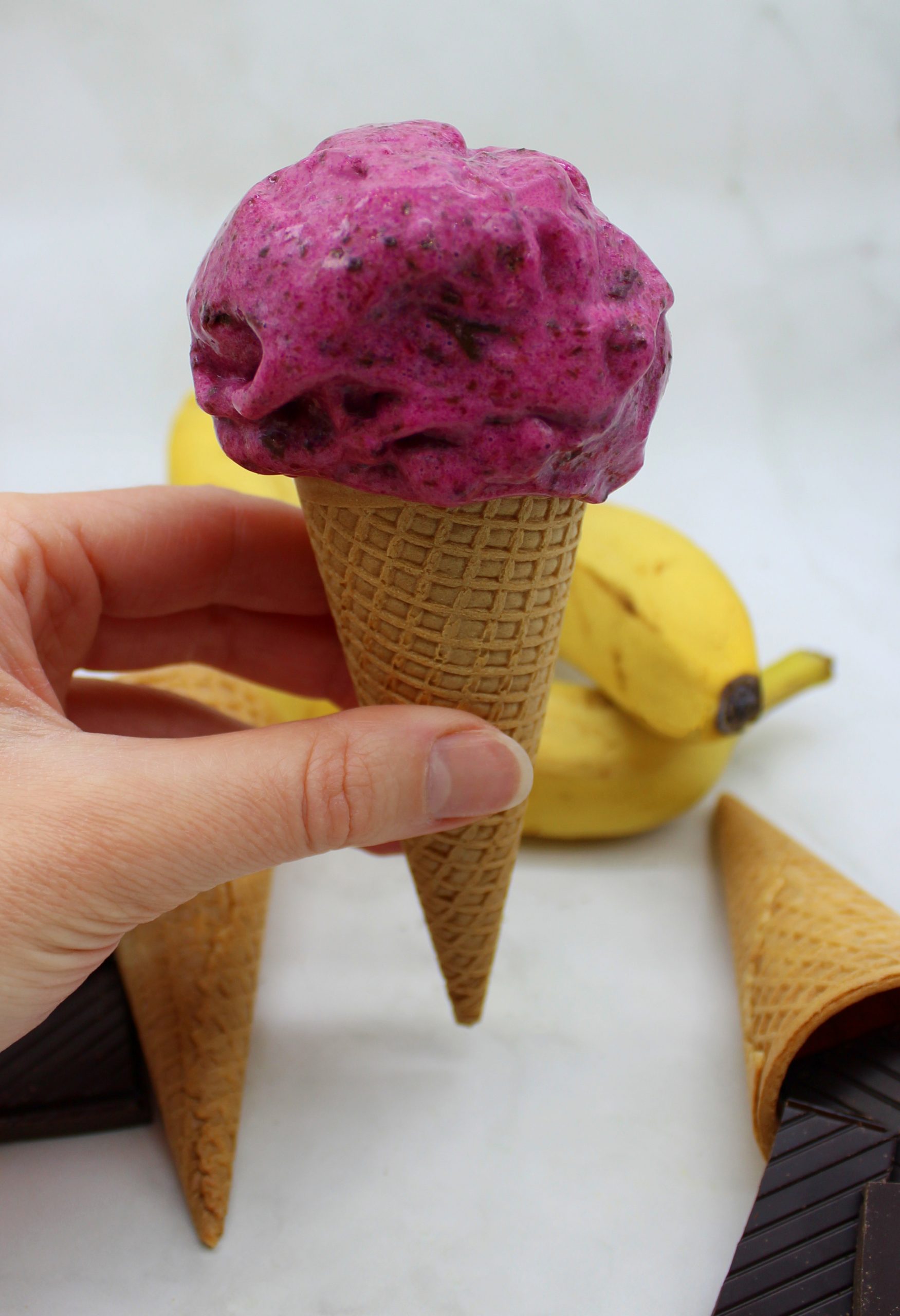 Vegan beetroot ice cream with chocolate pieces in a cone